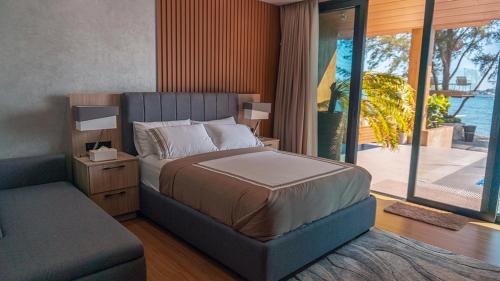 a bedroom with a bed and a couch and a window at Emon Pulo Beach Resort 