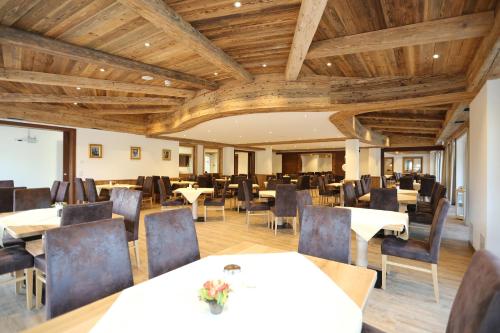 a restaurant with wooden ceilings and tables and chairs at Hotel Friedenseiche in Benediktbeuern