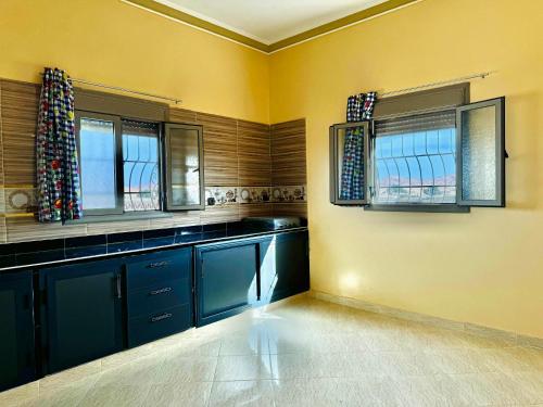 a kitchen with blue cabinets and two windows at Merzouga DesertView Apartment in Merzouga