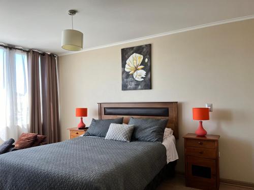1 dormitorio con 1 cama con 2 lámparas y 1 pintura en Depto 1 Dormitorio 1504 Central, en Temuco