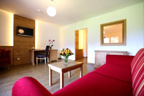 a living room with a red couch and a table at Hotel Friedenseiche in Benediktbeuern