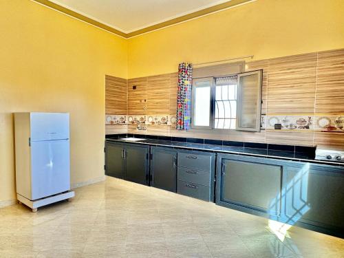 a kitchen with a white refrigerator and wooden cabinets at Merzouga DesertView Apartment in Merzouga
