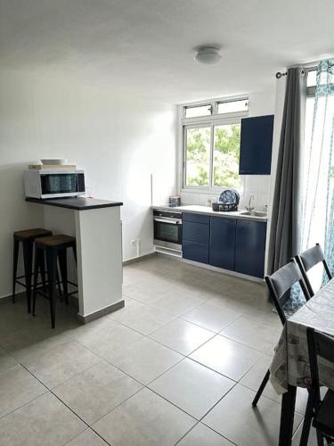 Il comprend une cuisine avec des placards bleus et du carrelage blanc. dans l'établissement Appartement F2, à Fort-de-France