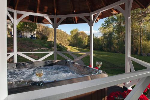 a hot tub on a gazebo with two glasses of wine at Antlers on the Creek Bed & Breakfast in Durango