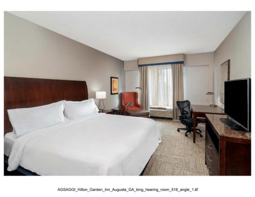 a hotel room with a bed and a desk and a television at Hilton Garden Inn Augusta in Augusta