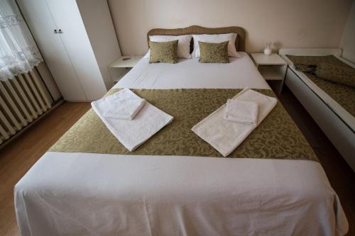 ein Schlafzimmer mit einem großen weißen Bett mit Handtüchern darauf in der Unterkunft Apartmani Pavlov in Aranđelovac