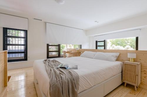 a white bedroom with a large bed and windows at Exclusivo Dúplex en Salamanca in Madrid