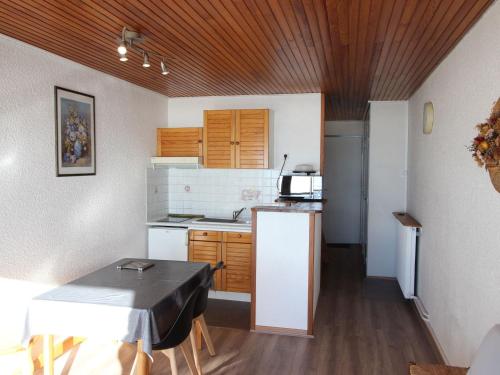 a small kitchen with a table and a refrigerator at Studio Chamrousse, 1 pièce, 4 personnes - FR-1-549-14 in Chamrousse