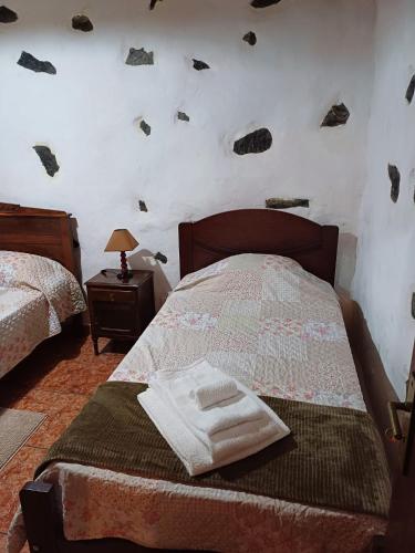 a bedroom with two beds with rocks on the wall at Casa da Queijaria in Faja Grande
