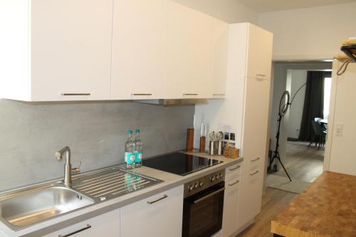 uma cozinha com armários brancos e um lavatório em Boutique Apartment im Zentrum em Paderborn