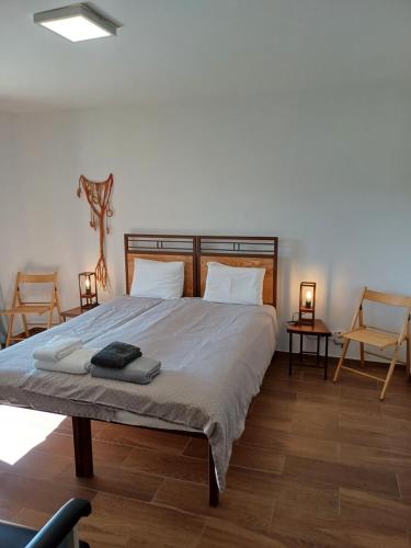 a bedroom with a large bed with two chairs at Oficina do Joe , Bungalow Gitte in Outeiro