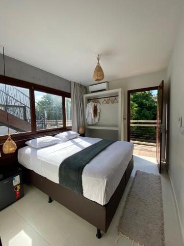 a bedroom with a large bed and a large window at Zenhousepipa in Pipa
