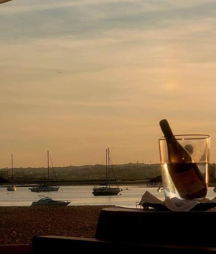 a bottle of wine sitting on a table with boats in the water at CerezinoFlats-Orange Bay Studio in Seixal