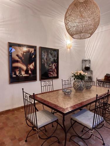 uma sala de jantar com uma mesa com cadeiras e um lustre em Riad Bamaga em Marraquexe