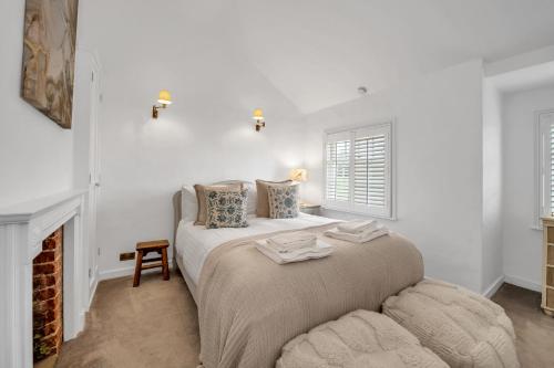 a white bedroom with a bed and a fireplace at Charming Church Walk - 2 bedroom property with parking in Long Melford