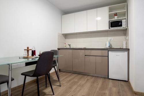 uma cozinha com armários brancos e uma mesa e cadeiras em Cherry Berry Apartmani em Eminovci