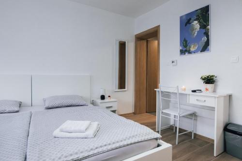 a white bedroom with a bed and a desk at Cherry Berry Apartmani in Eminovci
