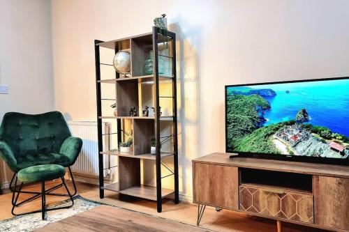 ein Wohnzimmer mit einem TV und einem grünen Stuhl in der Unterkunft Spacious Modern House with Great Transport Links and Long Stay Discounts in Thurcaston