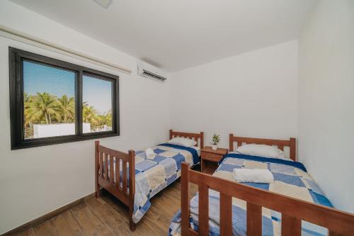 two beds in a room with a window at Beach House “El Rosario” in La Candelaria