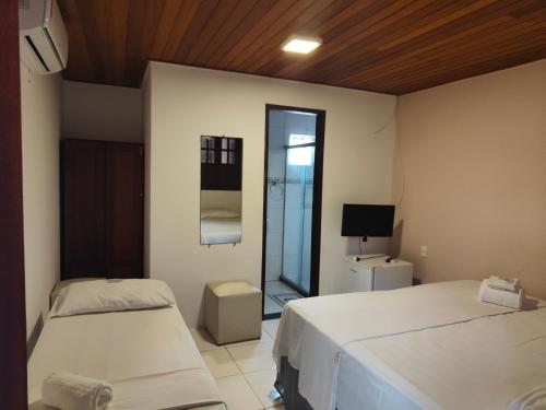 a bedroom with two beds and a television in it at Pousada Bellas Artes in Mata de Sao Joao