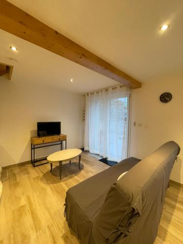 Schlafzimmer mit einem Bett, einem Tisch und einem TV in der Unterkunft Chez Gigi et Malou - gîte Brimbelle in Champ-le-Duc