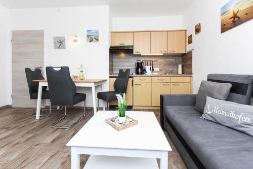ein Wohnzimmer mit einem Sofa und einem Tisch sowie eine Küche in der Unterkunft Ferienwohnungen Haus Boje in Neuharlingersiel