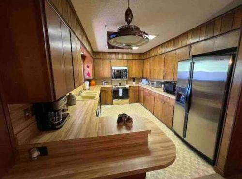 a kitchen with wooden cabinets and a stainless steel refrigerator at Large 3 Bedroom 70's Home - Benton, AR in Benton