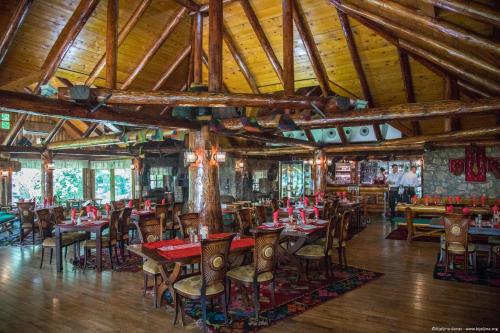 a restaurant with tables and chairs in a room with wooden ceilings at Etno selo Stanišići Hotel Leonida in Dijelovi