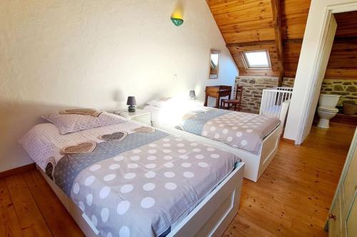 2 camas en una habitación con suelo de madera en Les gîtes du Kokopelli : Maupiti, en Plumelec