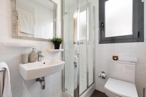 a white bathroom with a sink and a shower at Apartments Barcelona & Home Deco Eixample in Barcelona