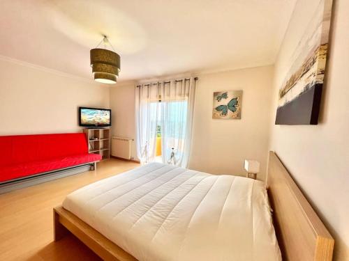een slaapkamer met een groot bed en een rode bank bij La villa du Paradis du Coto - Piscine-Mer&Surf in Coto