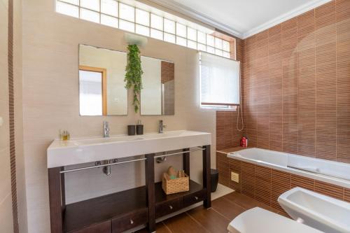 a bathroom with a sink and a tub and a mirror at Villa du Soleil by ACasaDasCasas in Ericeira