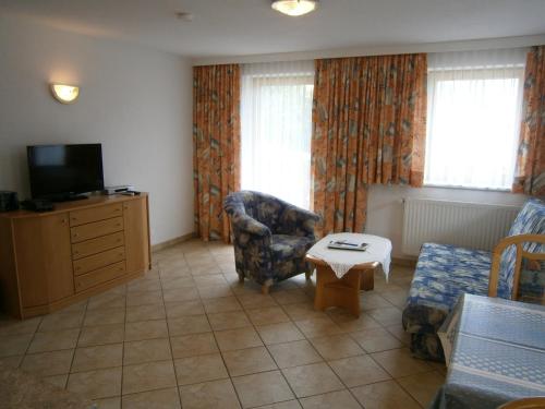 a living room with a tv and a chair and a table at Alpenview Lechtal in Holzgau