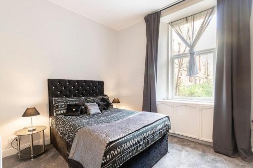 Un dormitorio con una cama grande y una ventana en Stunning Ground Floor flat in Southside. en Glasgow