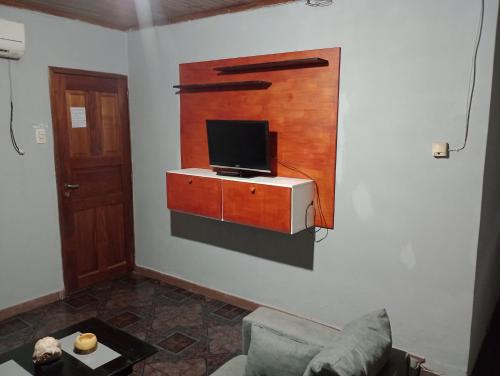 sala de estar con sofá y TV en la pared en Casona el ancla en Eldorado