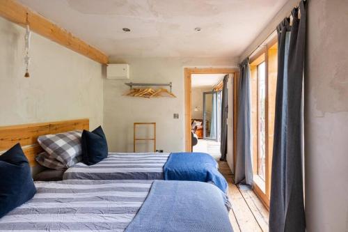 1 dormitorio con 2 camas y ventana en ‘The Little House on The Priory’ with Hot Tub, en Abergavenny