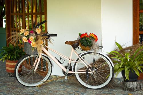 Una bicicleta estacionada al lado de un edificio con flores. en Hotel Campestre La Francesina, en Betania