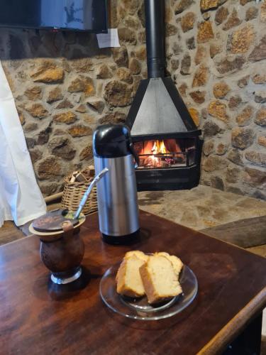 a table with a plate of bread and a fireplace at Alto da colina Caraá RS in Caraá