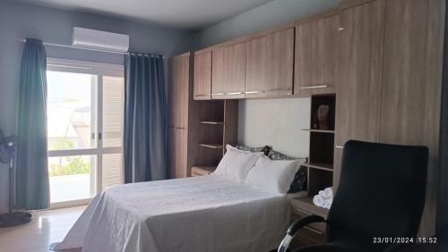 a bedroom with a bed and a window and a chair at Sobrado Completo Belíssima in Pelotas