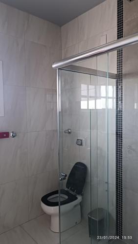 a bathroom with a toilet and a glass shower at Sobrado Completo Belíssima in Pelotas
