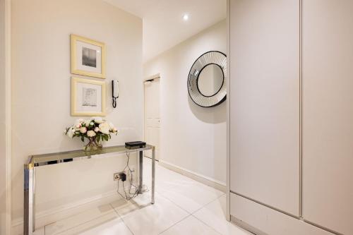 - un couloir avec un miroir et une table fleurie dans l'établissement Marylebone Luxury 2 Bed Appartment, à Londres