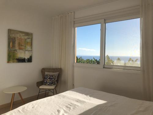 1 dormitorio con ventana, 1 cama y 1 silla en Vivienda Atlantico en Tazacorte