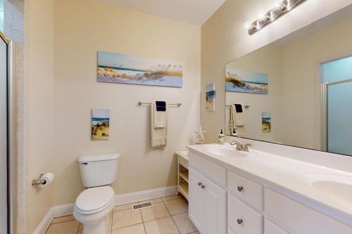 een badkamer met een toilet, een wastafel en een spiegel bij Shore Thing in Surf City