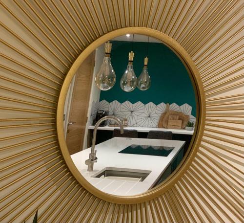 een spiegel aan een muur met een wastafel en verlichting bij Parkside Lodge - Luxury Coastal Hideaway for Two in Brixham