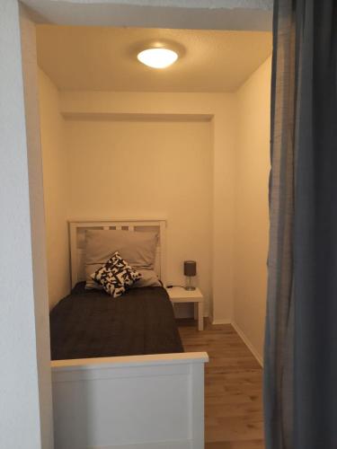 a small bedroom with a bed and a lamp at Ferienwohnung K1 in Hambühren