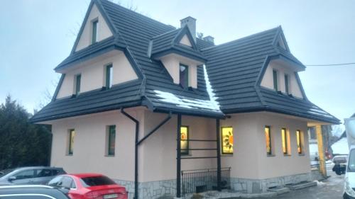 une maison avec un toit en gambrel recouvert de neige dans l'établissement Apartamenty Pokoje Zakopane, à Zakopane