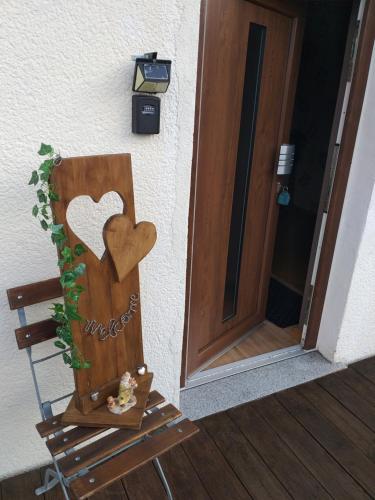 une porte en bois avec un cœur à côté d'une chaise dans l'établissement Großes Apartment "Rena", à Baumholder