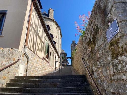 um conjunto de escadas ao lado de um edifício com uma placa em La maison sur les remparts em Domfront