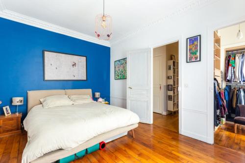 une chambre avec un lit avec un mur bleu dans l'établissement Spacious and pleasant nest 2 steps from Montmartre, à Paris