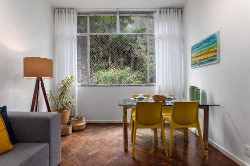 uma sala de estar com uma mesa e cadeiras e uma janela em 2 Quartos - Amplo e confortável perto do Metro Flamengo no Rio de Janeiro